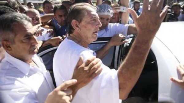 A defesa do médium João Teixeira de Faria, o João de Deus, de 76 anos, prepara para esta segunda-feira (17) o habeas corpus para reverter o pedido de prisão preventiva em domiciliar com tornozeleira. O advogado Alberto Toron afirmou que devem ser considerados a idade elevada e o estado de saúde dele. Lembrou que João de Deus passou por um tratamento de combate ao câncer e é cardíaco.  O médium é denunciado por mais de 300 mulheres, incluindo jovens e casos de crianças, de abuso sexual. Algumas acusações têm mais de 30 anos. Elas relatam que os abusos, em geral, ocorriam durante os atendimentos espirituais. Ele se entregou no domingo (16), por volta das 16h20, na zona rural de Abadiânia, em Goiás, depois de longa negociação.  A primeira noite do médium, após sua entrega à polícia, foi no Complexo Prisional de Aparecida de Goiânia, denominado Núcleo de Custódia. João de Deus, segundo os policiais, ficaria em uma cela de 16 metros quadrados com cama, pia e vaso sanitário. A defesa pediu que João de Deus fosse colocado em uma cela sozinho.  INTERROGATÓRIO O médium prestou depoimento por mais de três horas na delegacia em Goiânia. O interrogatório terminou por volta das 22h. Ele foi questionado sobre 15 depoimentos de mulheres que o denunciaram por abuso sexual, negou as acusações e apresentou sua versão sobre as denúncias.  Após o interrogatório, João de Deus foi levado para fazer exame de corpo de delito no IML (Instituto Médico-Legal) e depois seguiu para Complexo Prisional de Aparecida de Goiânia. Antes do depoimento, o delegado-chefe, André Fernandes, afirmou que o médium seria questionado sobre cada um dos 15 depoimentos, separadamente. Segundo ele, as denúncias envolvem distintos crimes, como os mais variados atentados a costumes e fraudes.  \
